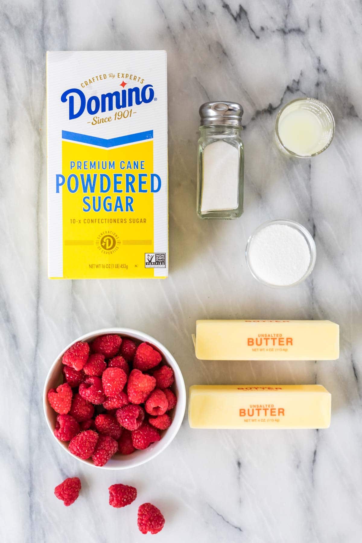 Overhead view of ingredients including powdered sugar, raspberries, butter, and more.