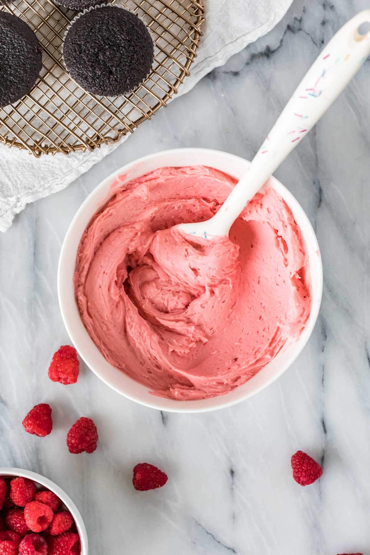 Bowl of pink raspberry frosting made with fresh raspberries.