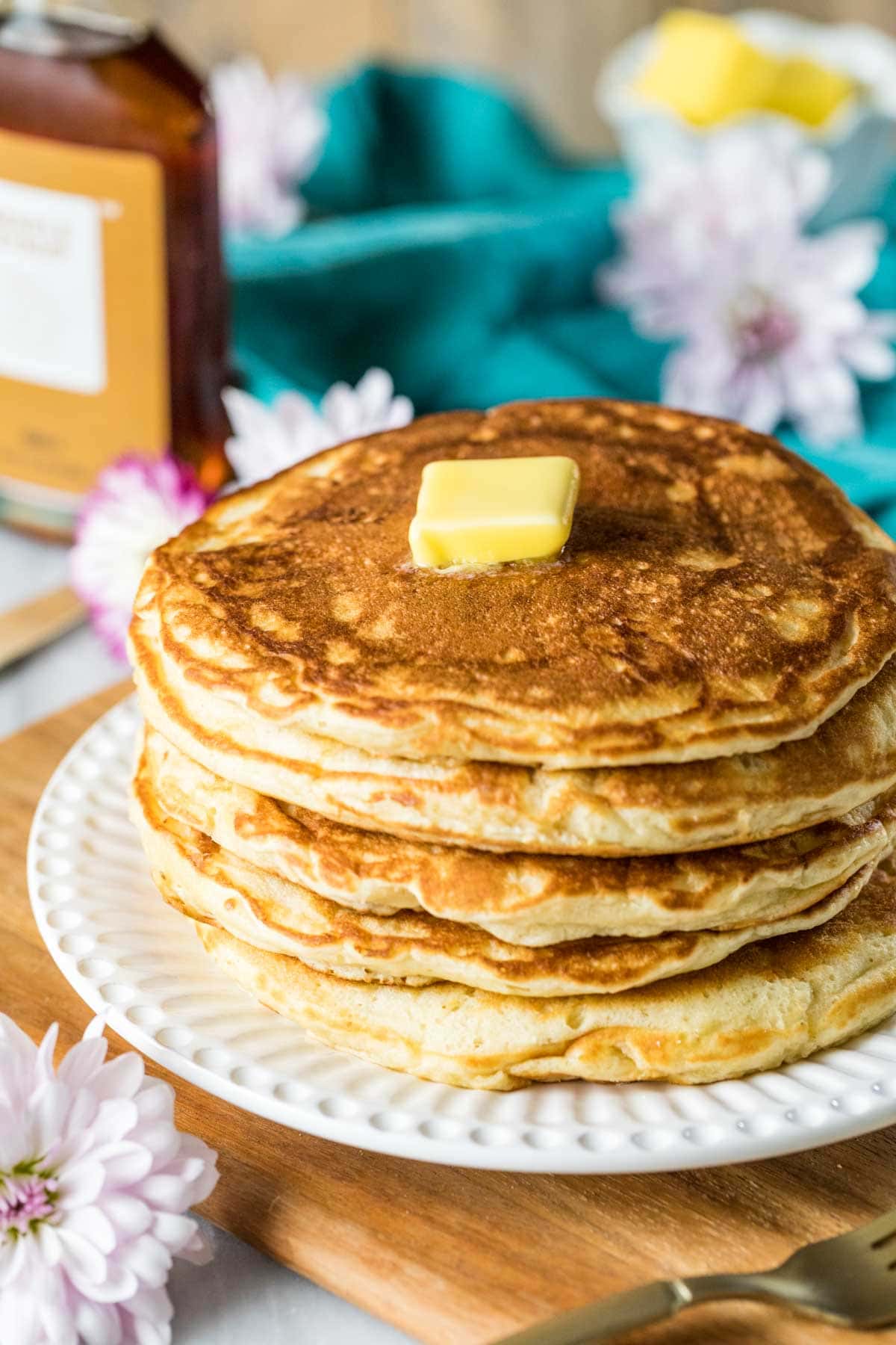 Ein hoher Stapel Sauerteig-Pfannkuchen mit einem Stück Butter darauf.