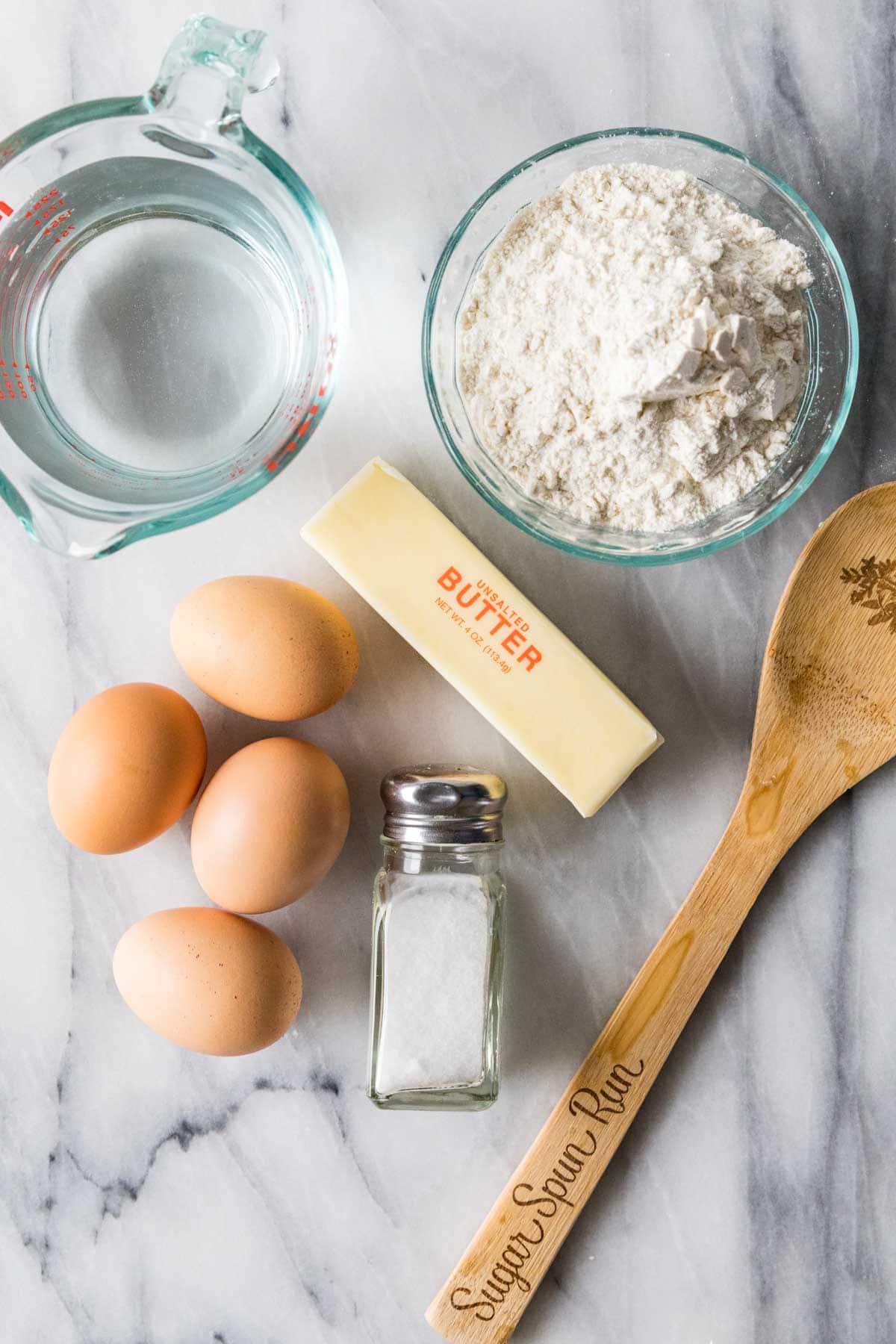 Overhead view of ingredients including eggs, butter, flour, water, and salt.