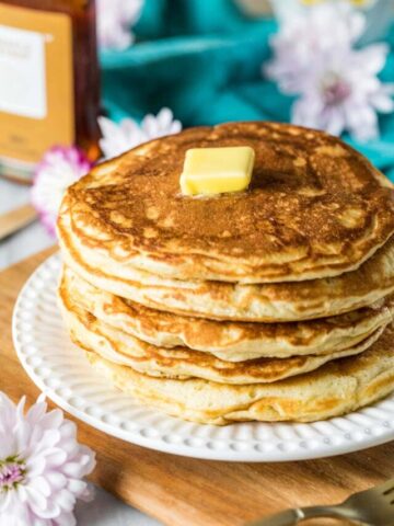 Tall stack of sourdough discard pancakes with a pat of butter on top.