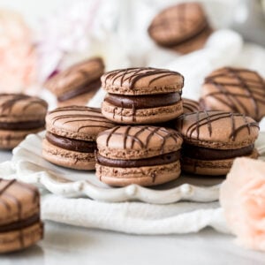 Plate of chocolate macarons drizzled with chocolate.