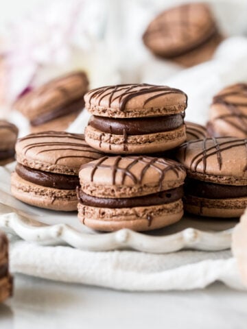 Plate of chocolate macarons drizzled with chocolate.