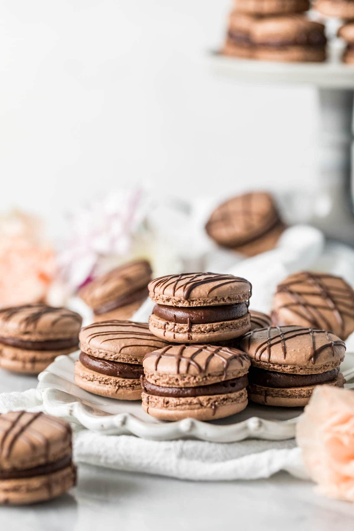 Plate of chocolate macarons drizzled with chocolate.