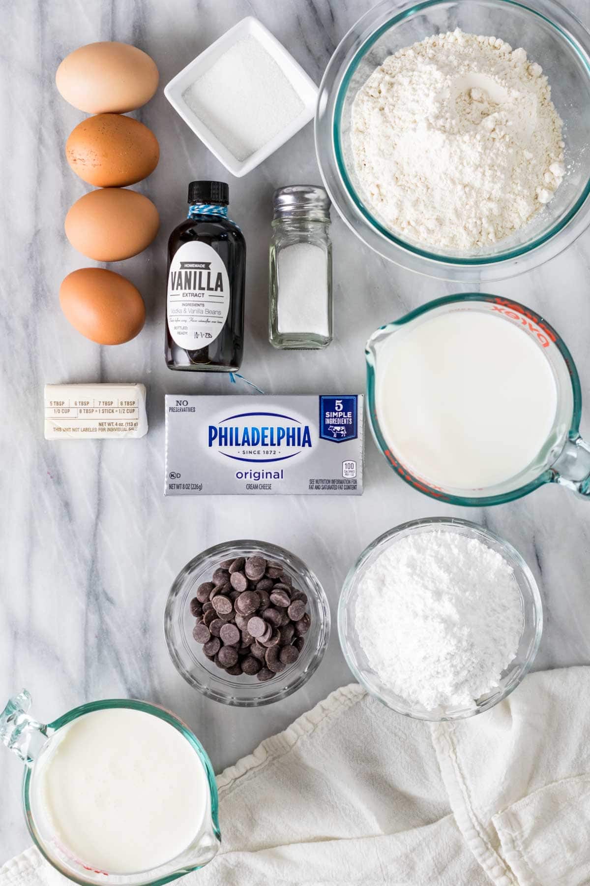 Overhead view of ingredients including eggs, vanilla, cream cheese, and more.