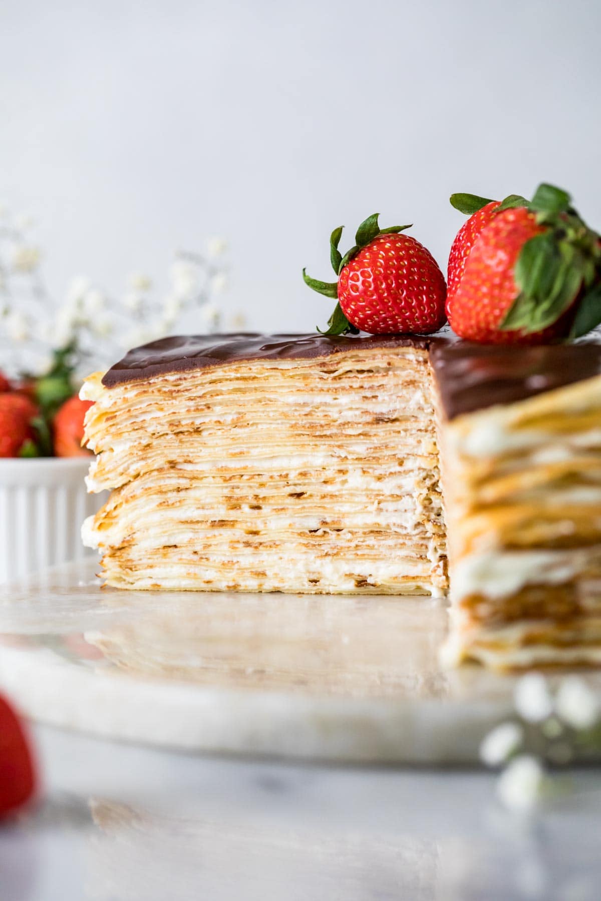 Head on view of a cross section of cake made from stacked crepe layers and whipped cream cheese filling.