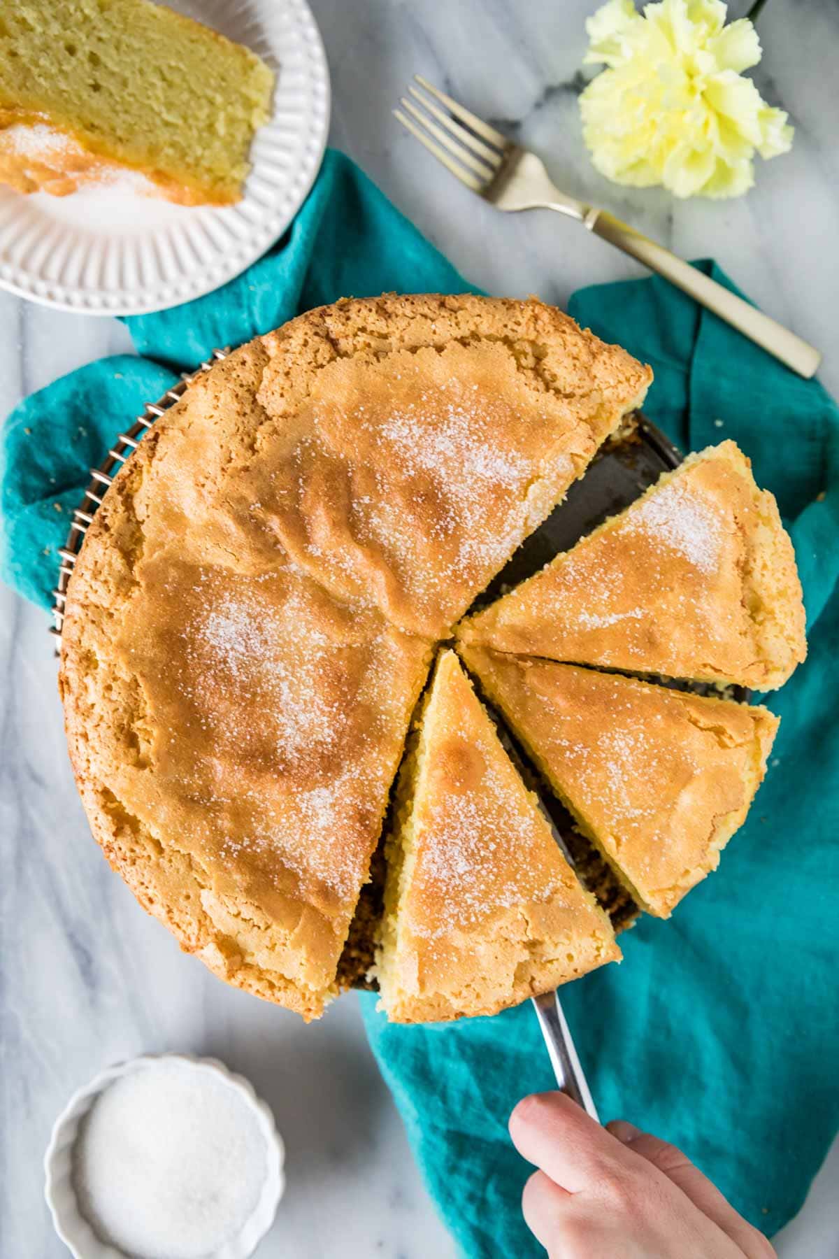 Overhead view of olive oil cake with three slices cut and and ready to serve.