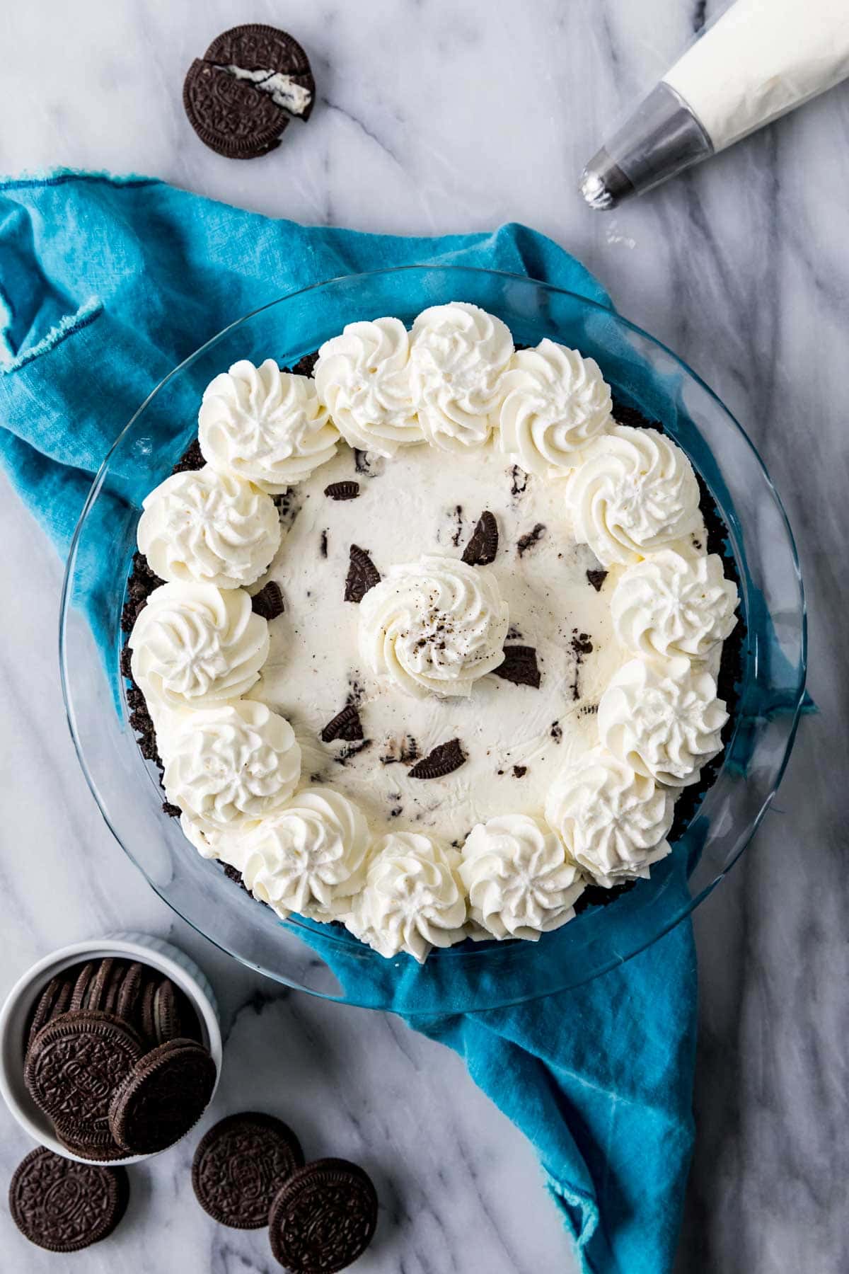 Draufsicht auf einen Kuchen mit Oreo-Kruste, zerbrochenen Oreo-Stücken und einem Schlagsahne-Topping.