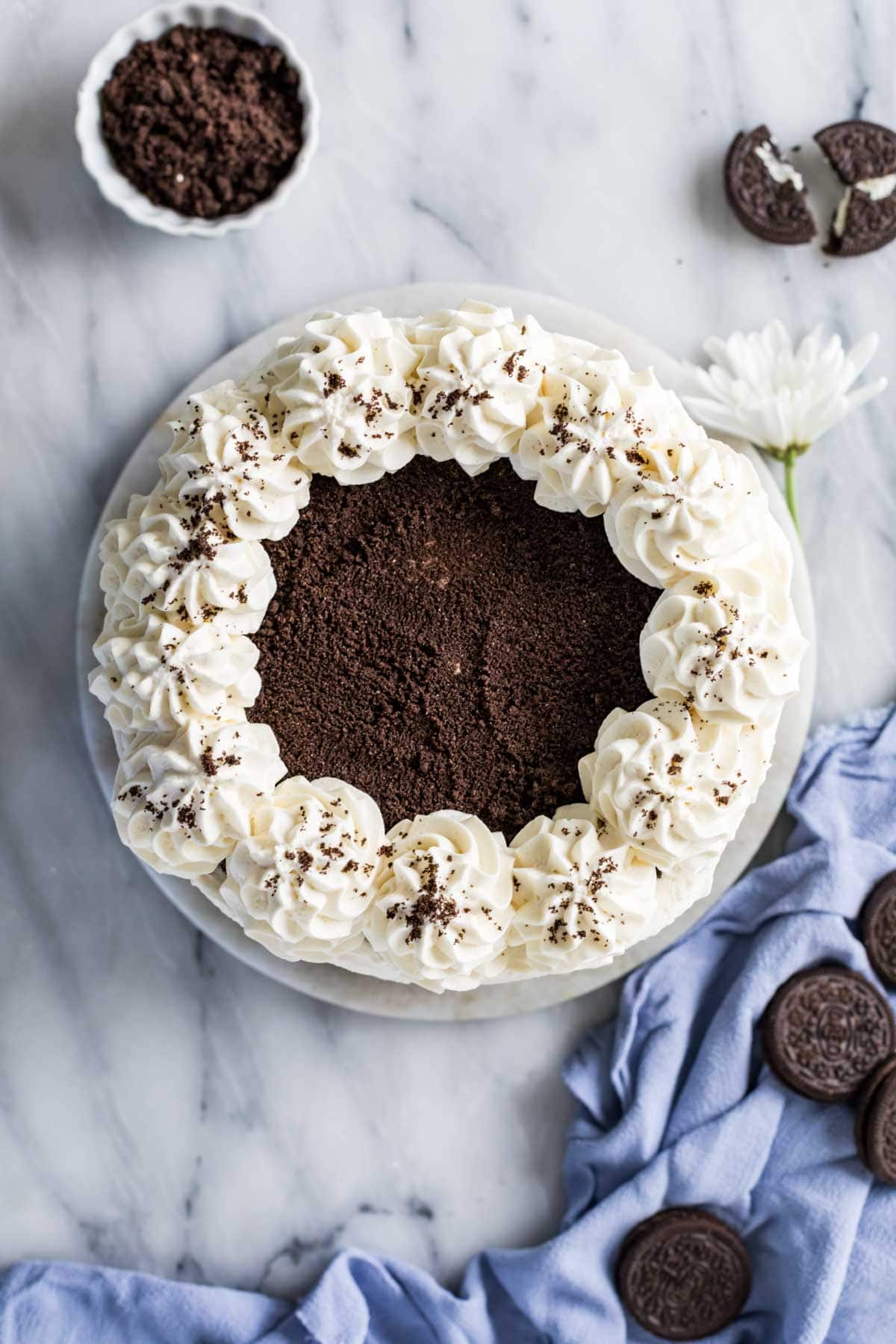 Overhead view of a cake topped with chocolate ganache and a border of piped icing swirls.