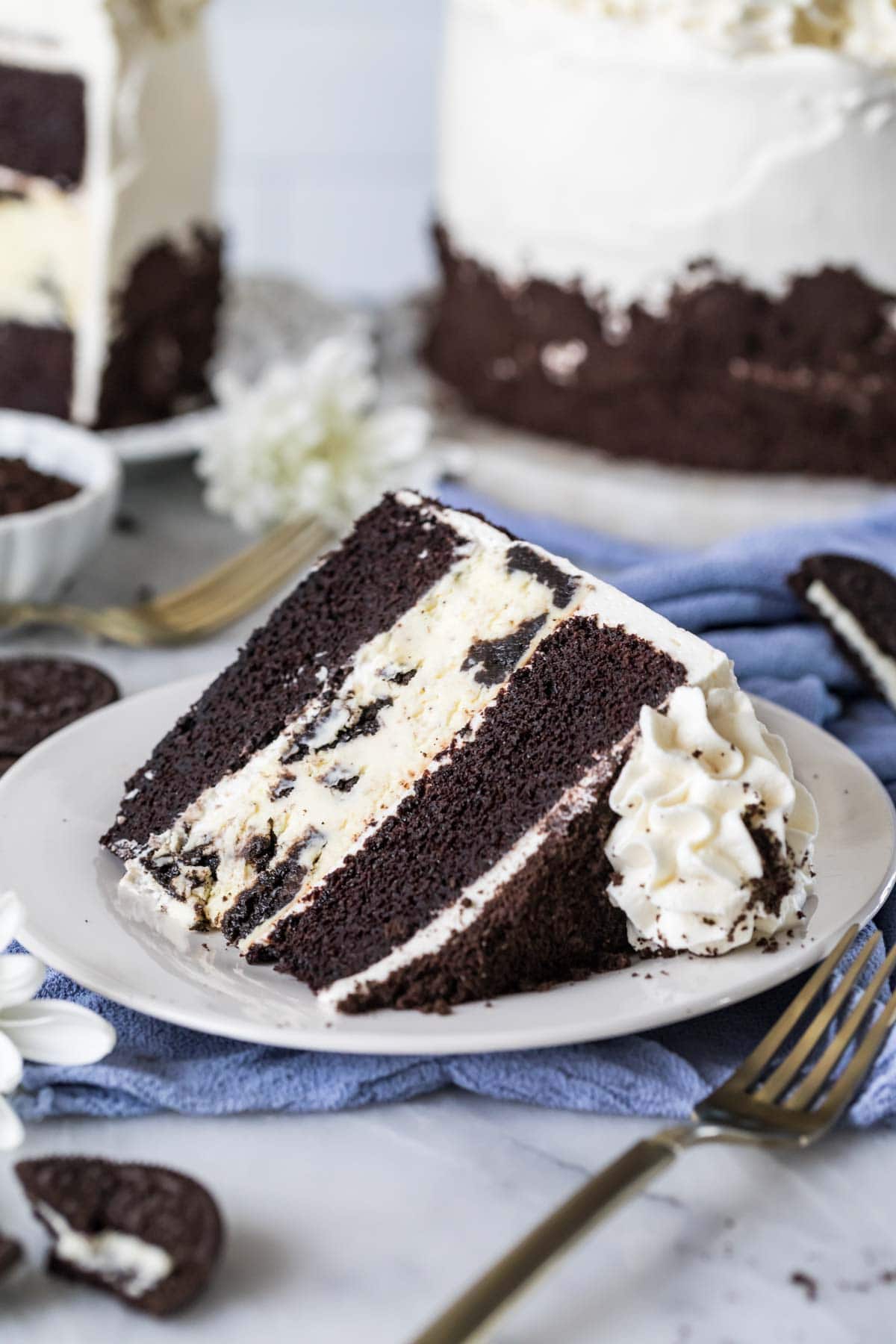 Slice of cake consisting of two layers of chocolate cake sandwiching an oreo cheesecake.