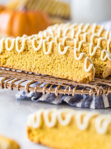 Pumpkin biscotti drizzled with white chocolate on a metal cooling rack.
