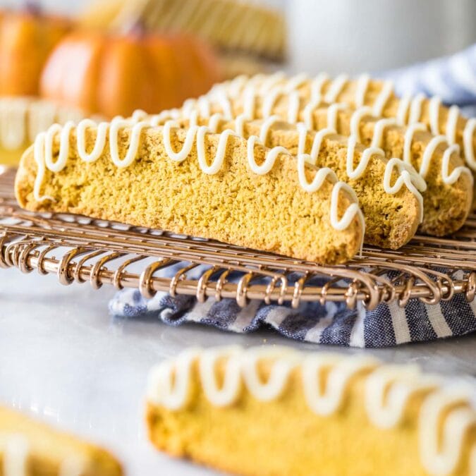 Pumpkin biscotti drizzled with white chocolate on a metal cooling rack.