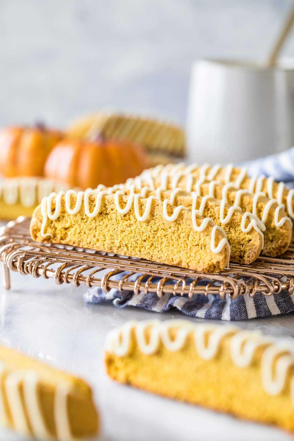 Pumpkin biscotti drizzled with white chocolate on a metal cooling rack.