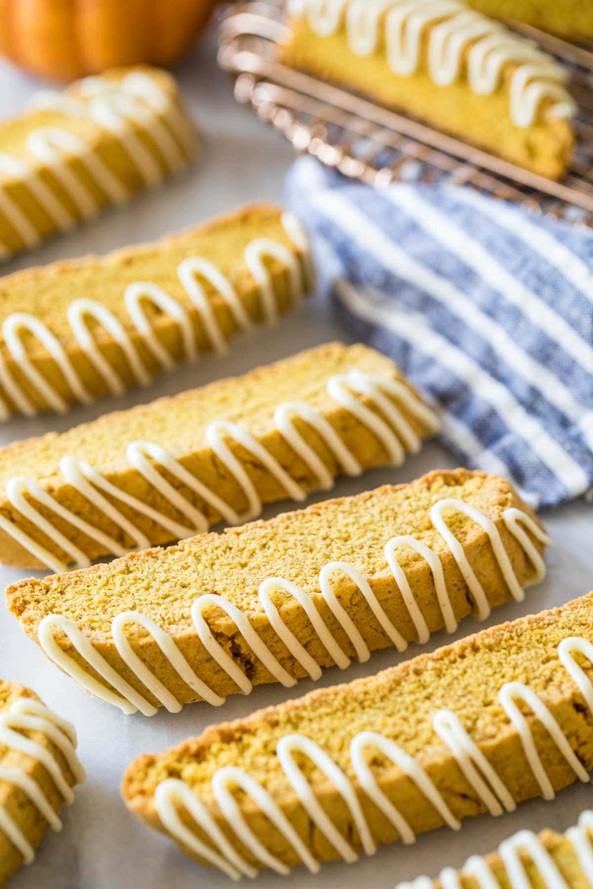 Pumpkin flavored biscotti drizzled with white chocolate lined up in a row.