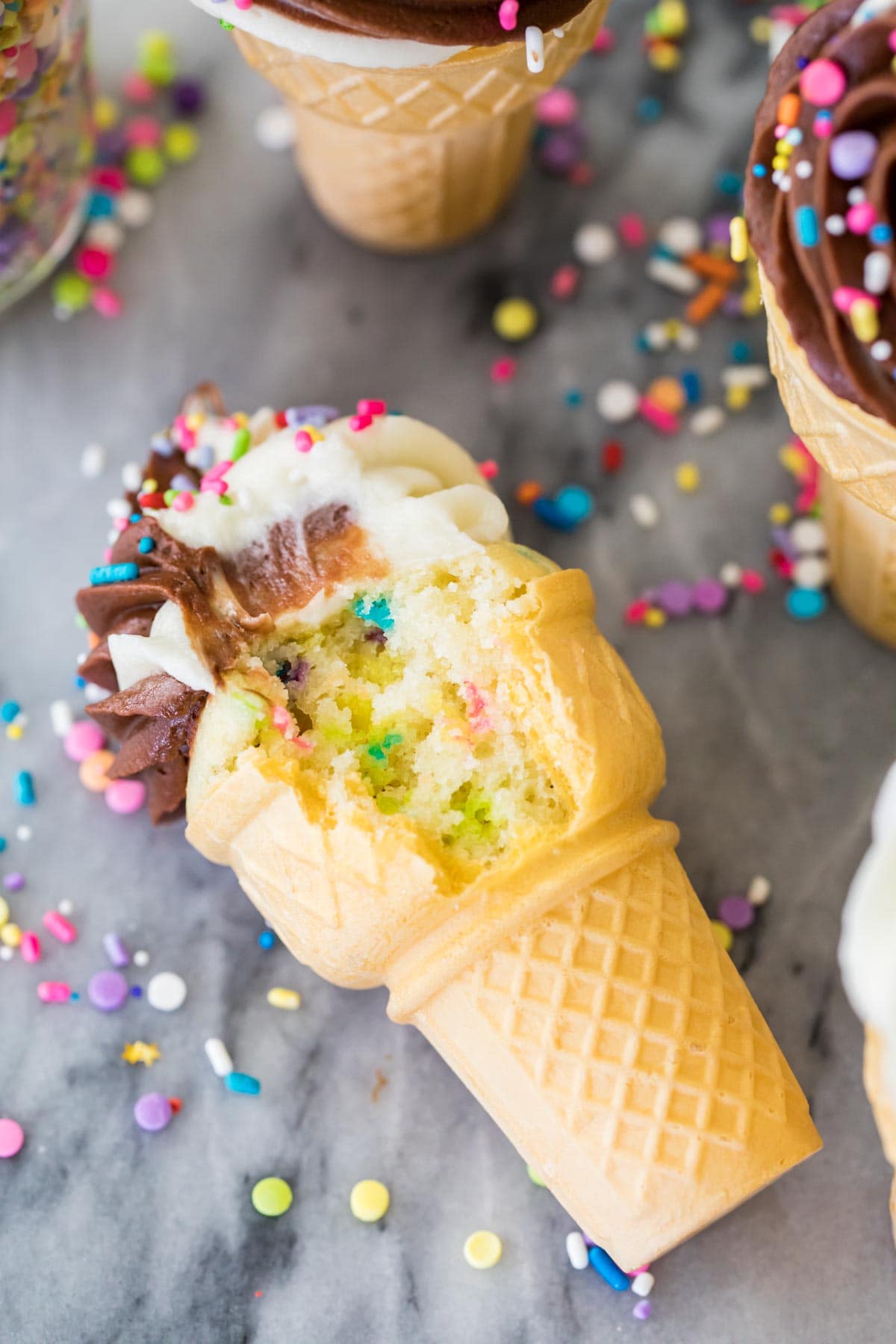 Ice cream cone bitten to show sprinkle filled cake batter inside.
