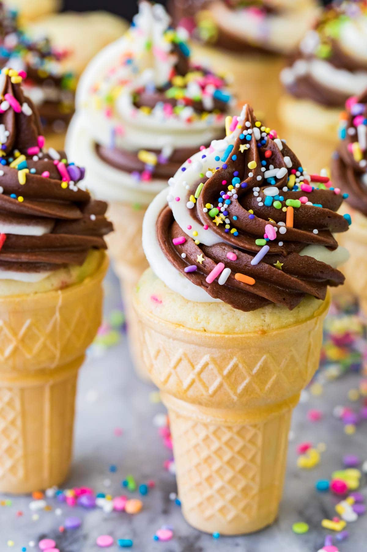 Ice cream cone cupcakes topped with a chocolate vanilla frosting swirl and sprinkles.
