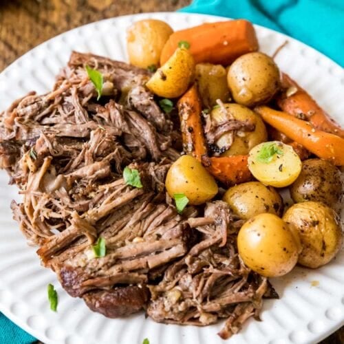 Plate of beef pot roast with baby potatoes and carrots.