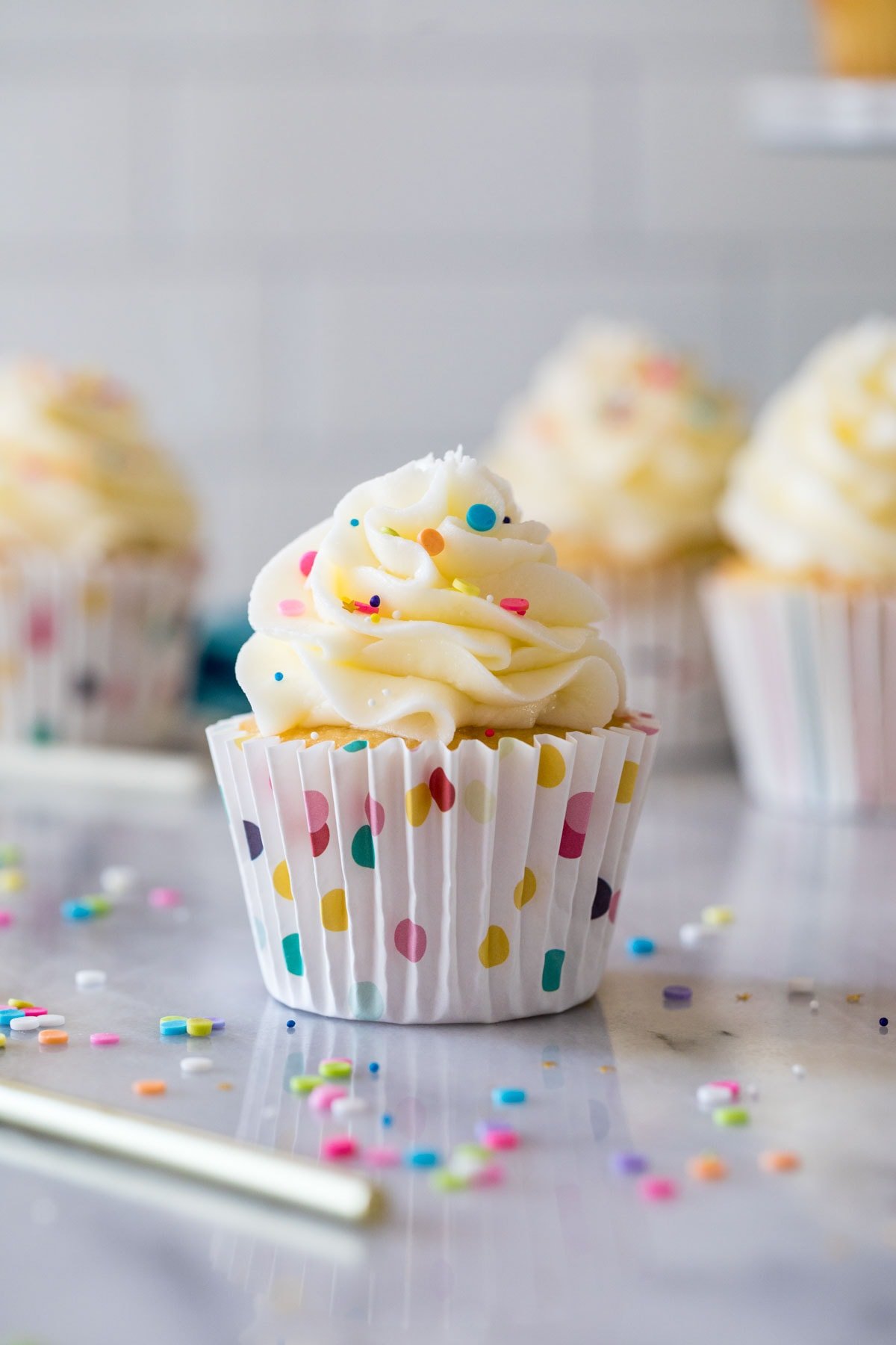 Strooi de gegarneerde cupcake in een kleurrijke polka dot cupcake wrapper.