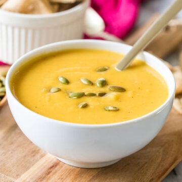 Bowl of butternut squash soup topped with roasted pumpkin seeds.
