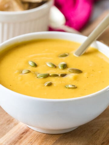 Bowl of butternut squash soup topped with roasted pumpkin seeds.