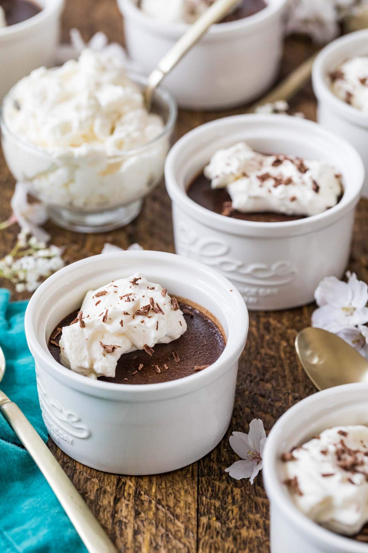 Ramekins of pot de creme topped with whipped cream and chocolate shavings.