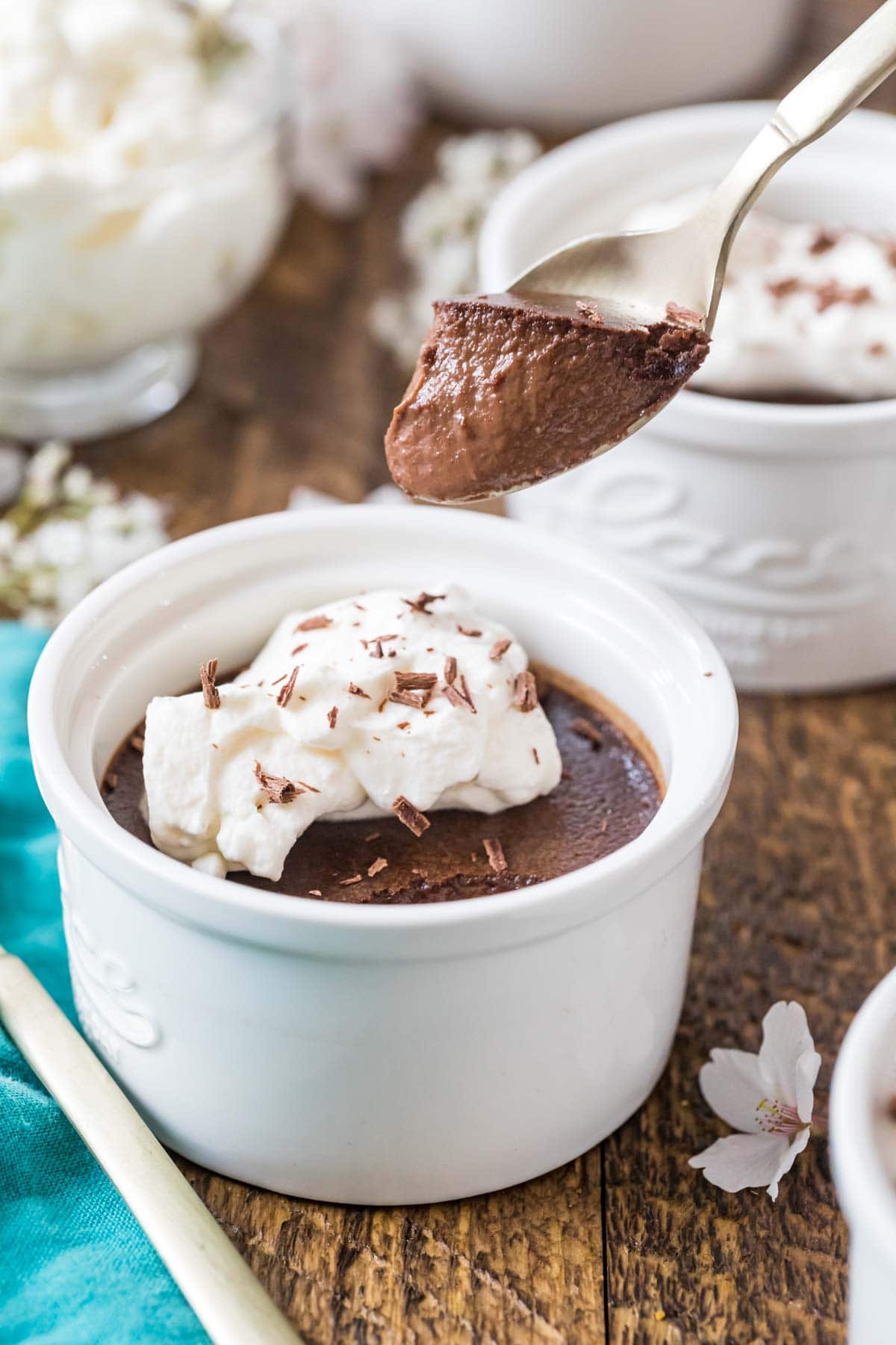 Spoon scooping chocolate pot de creme out of a white ramekin.