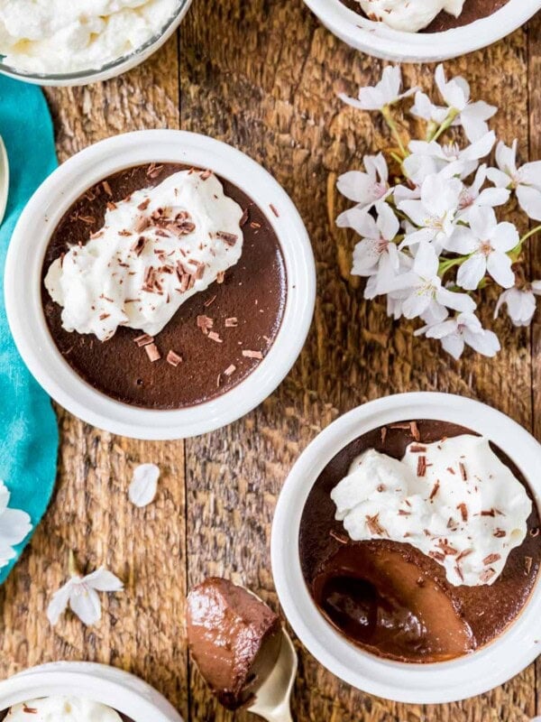Overhead view of chocolate pot de creme topped with whipped cream and chocolate shavings in small white ramekins.