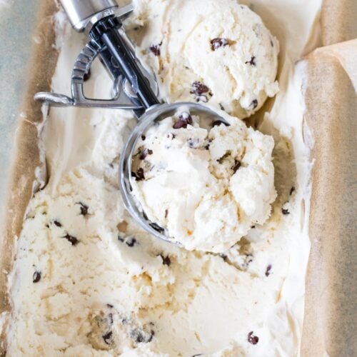Ice cream scoop resting in a container of homemade cookie dough ice cream.