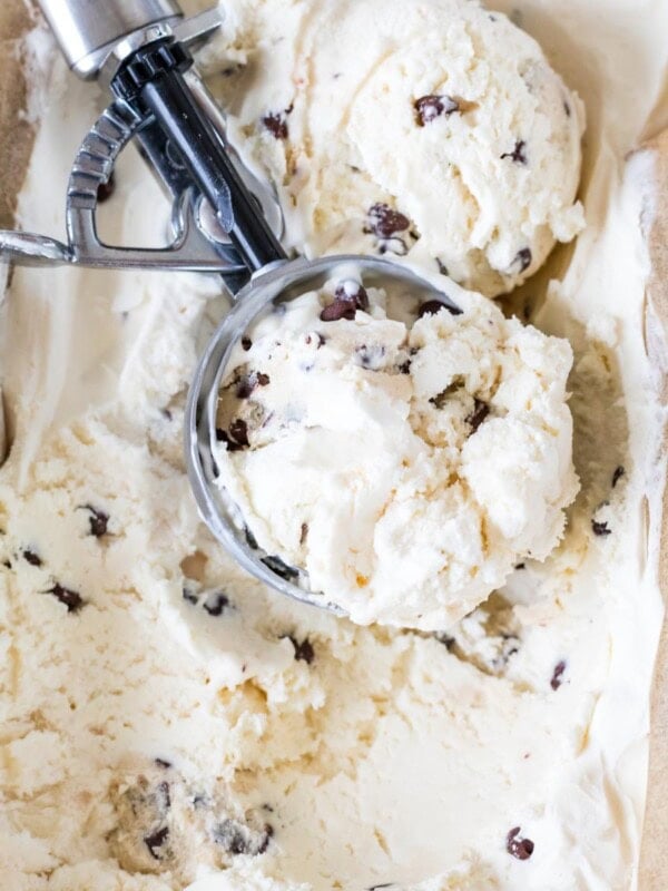Ice cream scoop resting in a container of homemade cookie dough ice cream.