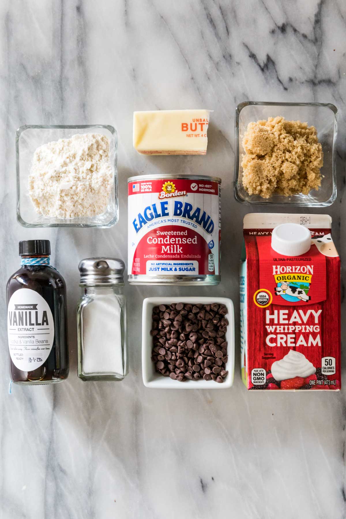 Overhead view of ingredients including condensed milk, heavy whipping cream, brown sugar, chocolate chips, and more.