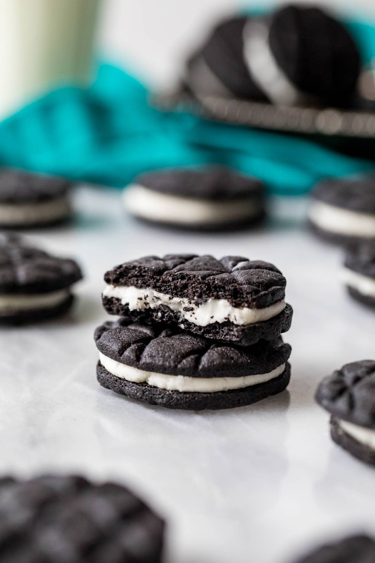 Two homemade Oreo cookies with stacked on top of each other with the top cookie missing a bite.