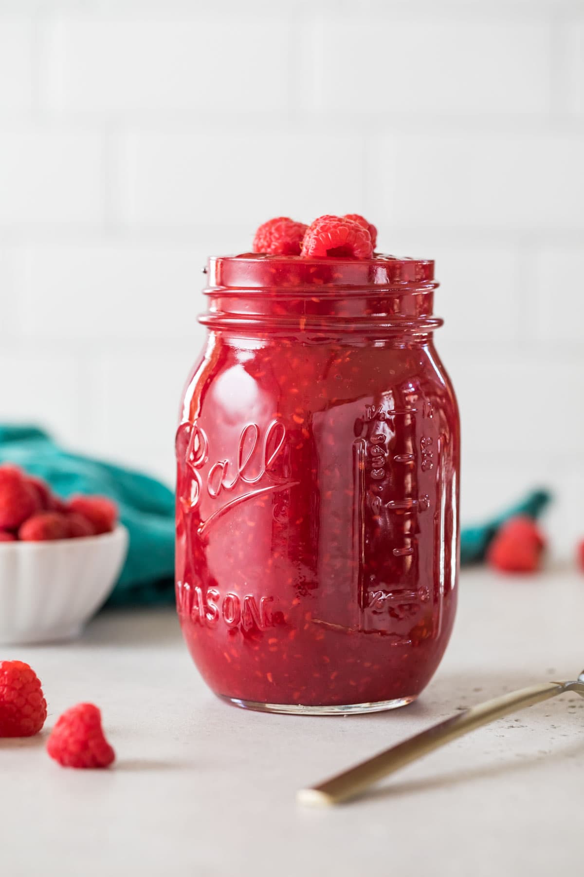 Einmachglas mit hausgemachter Himbeersauce, garniert mit frischen Himbeeren.