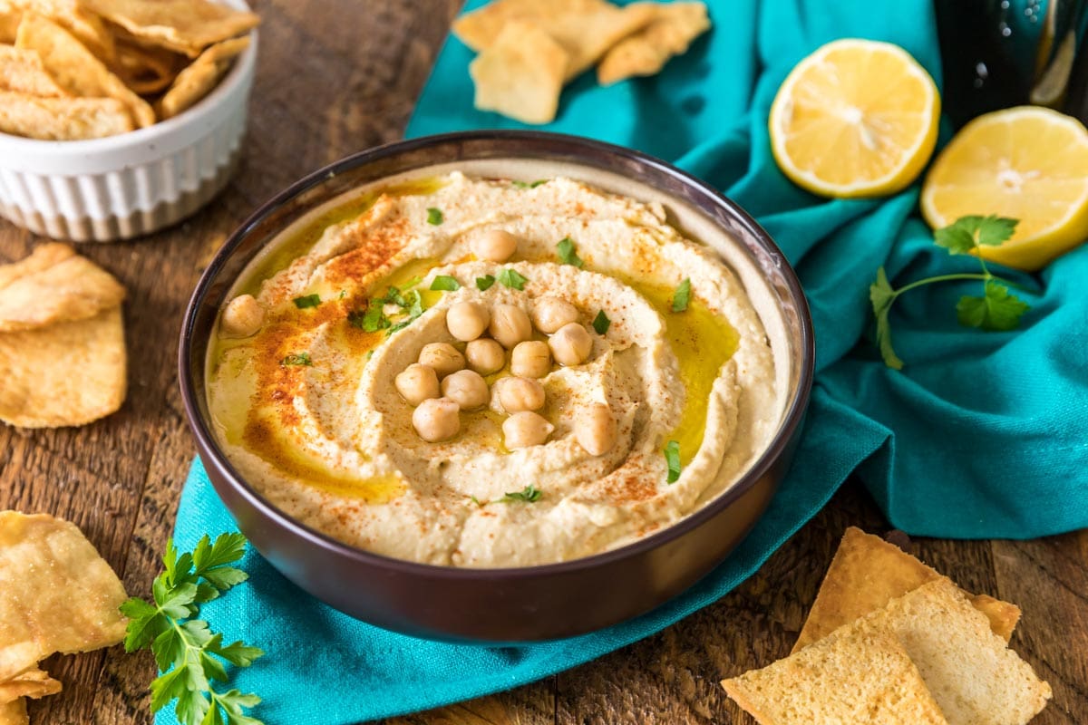 Large bowl of homemade hummus topped with paprika, parsley, olive oil, and chickpeas.