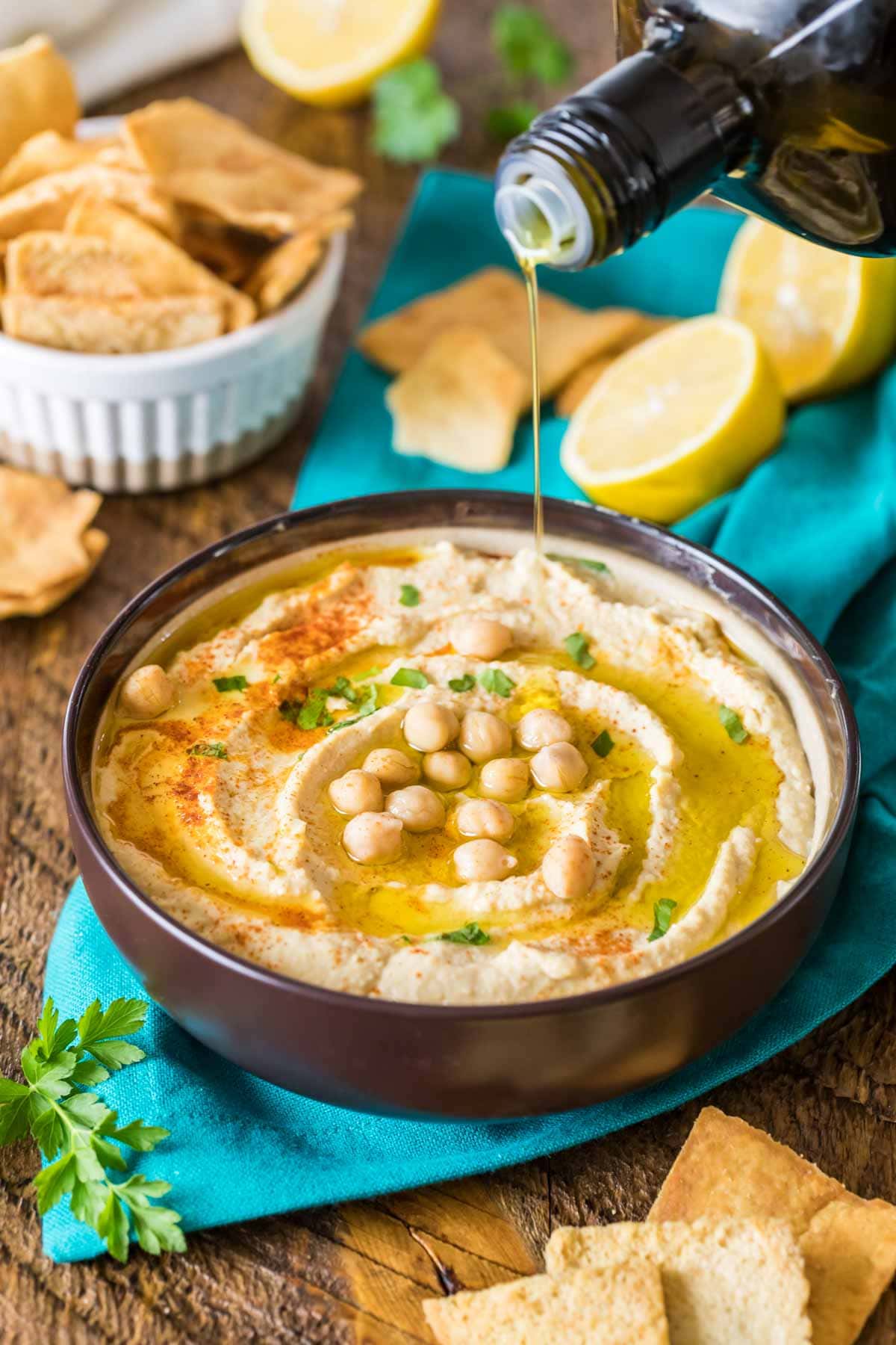 Large bowl of homemade hummus topped with paprika, parsley, olive oil, and chickpeas.