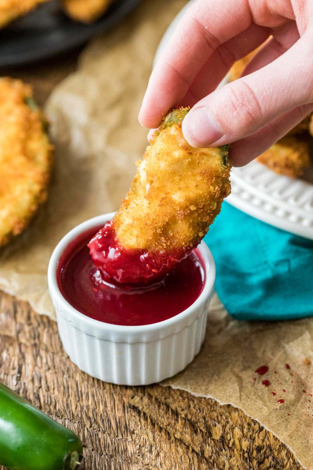 Jalapeno popper being dipped into a raspberry dipping sauce.