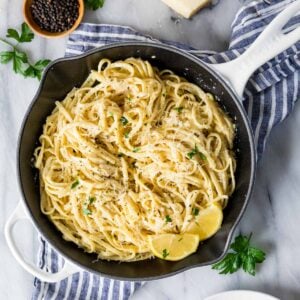 Overhead view of a skillet filled with lemon pasta and fresh lemon slices.