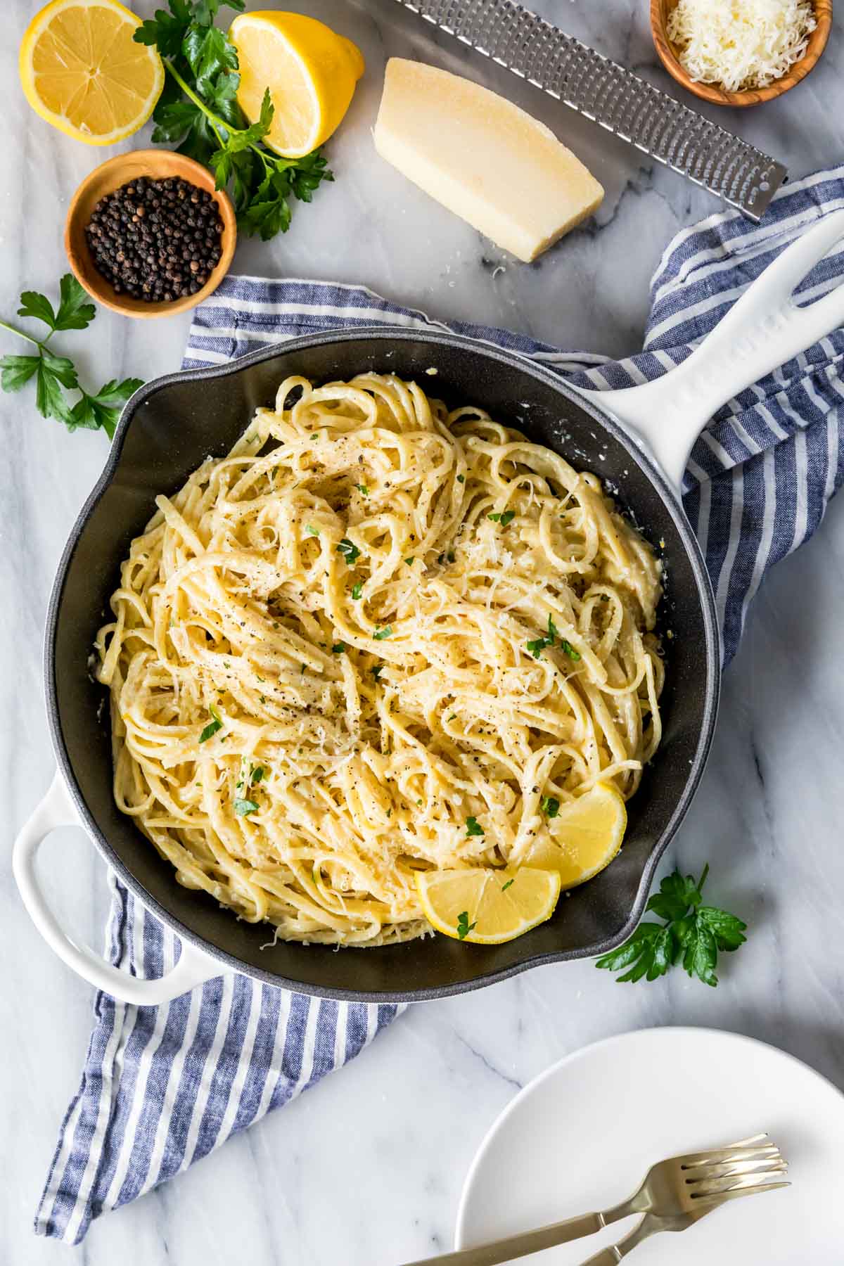 Overhead view of a skillet filled with lemon pasta and fresh lemon slices.