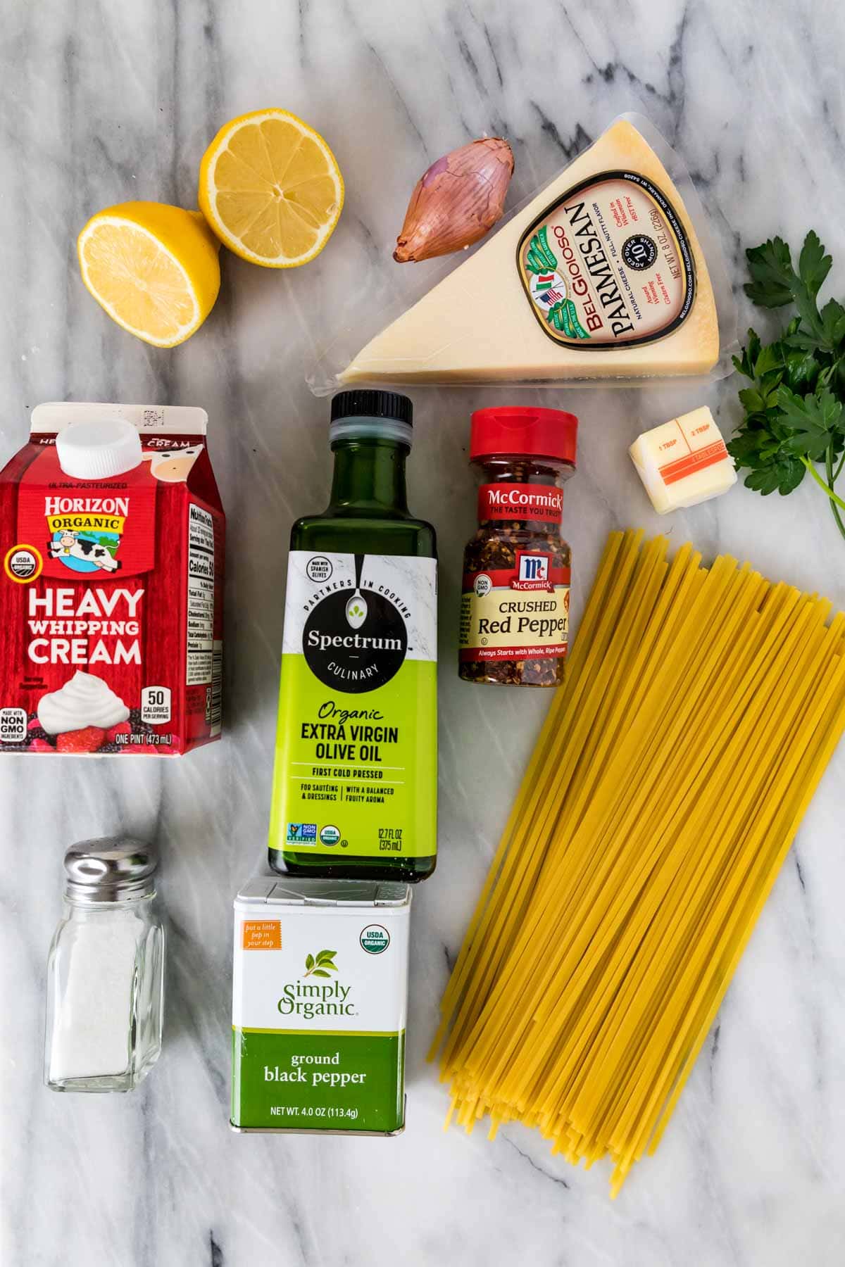 Overhead view of ingredients including lemons, parmesan, heavy cream, linguine pasta, and more.