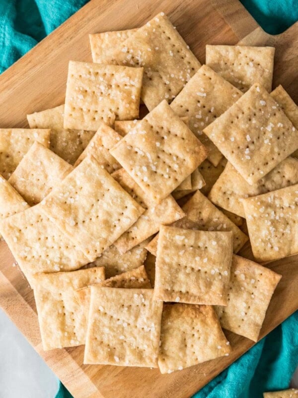 Overhead view of sourdough crackers scattered across a wooden cutting board.