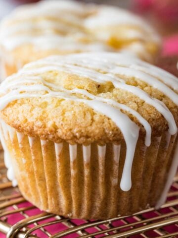 Peach muffins drizzled with vanilla glaze on a cooling rack.