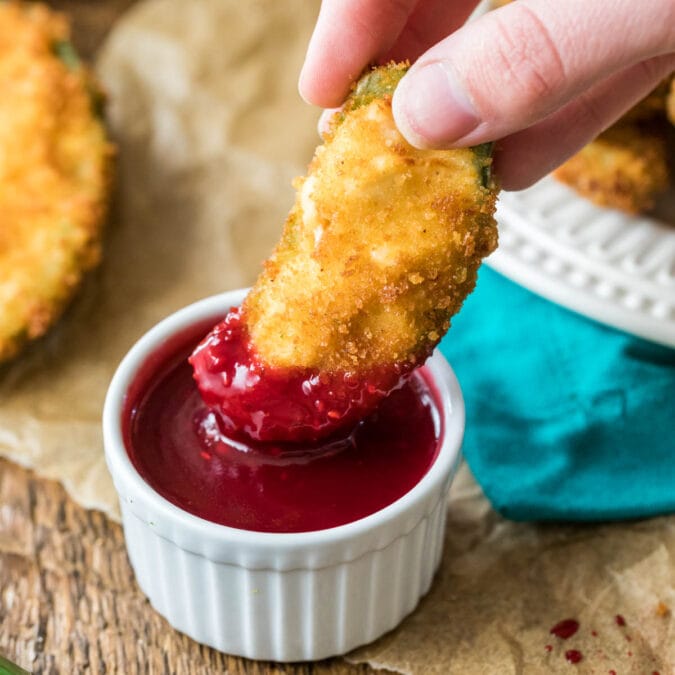 Jalapeno popper being dipped into a raspberry dipping sauce.