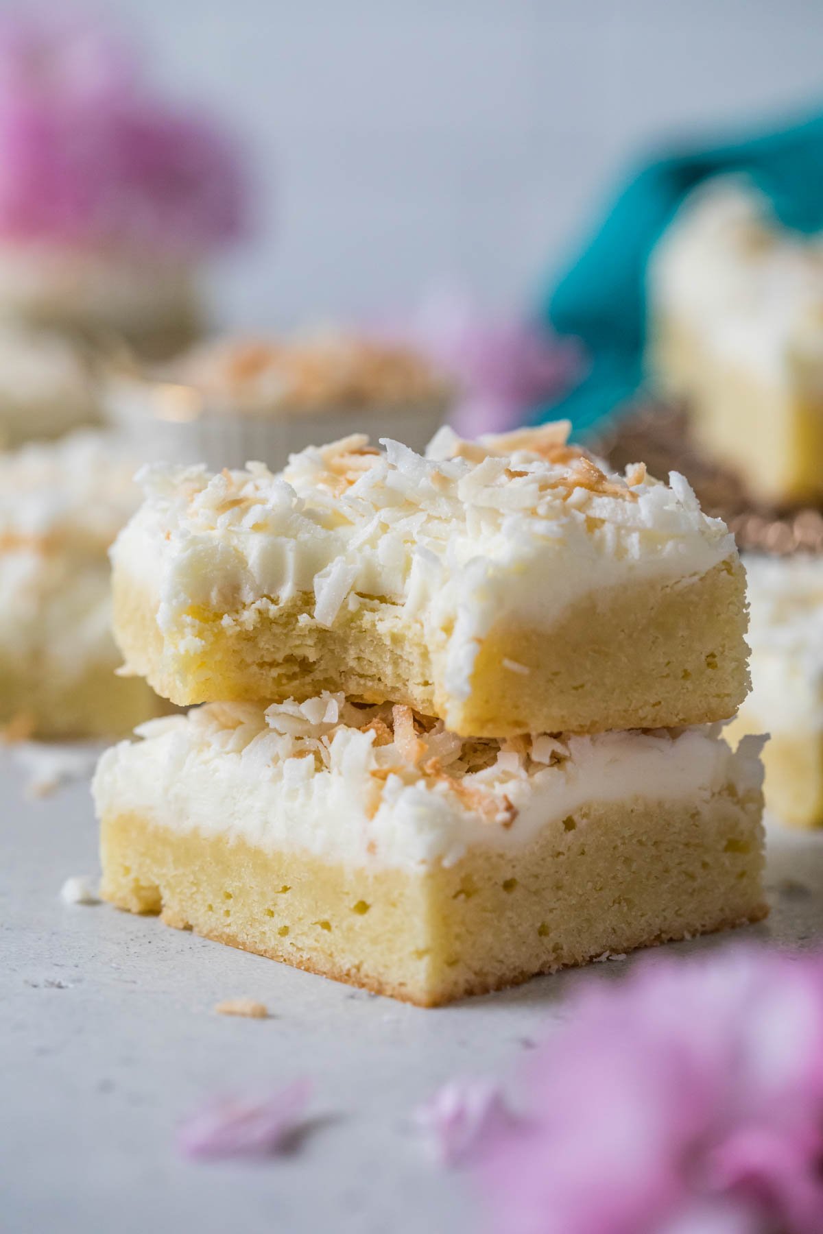 Two coconut cream bars stacked on top of each other, with the top bar missing a bite.