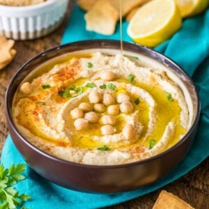 Large bowl of homemade hummus topped with paprika, parsley, olive oil, and chickpeas.