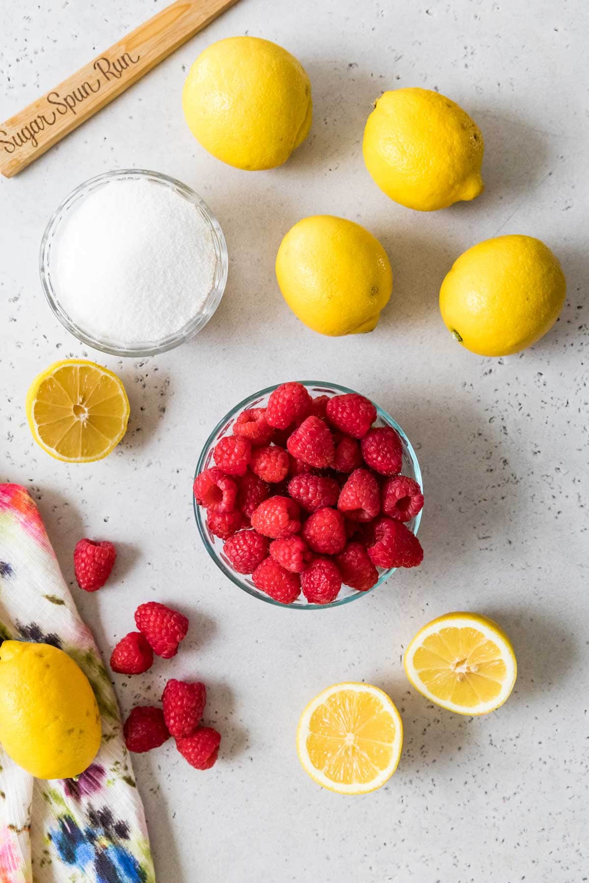 Overhead view of ingredients including lemons, raspberries, and sugar.