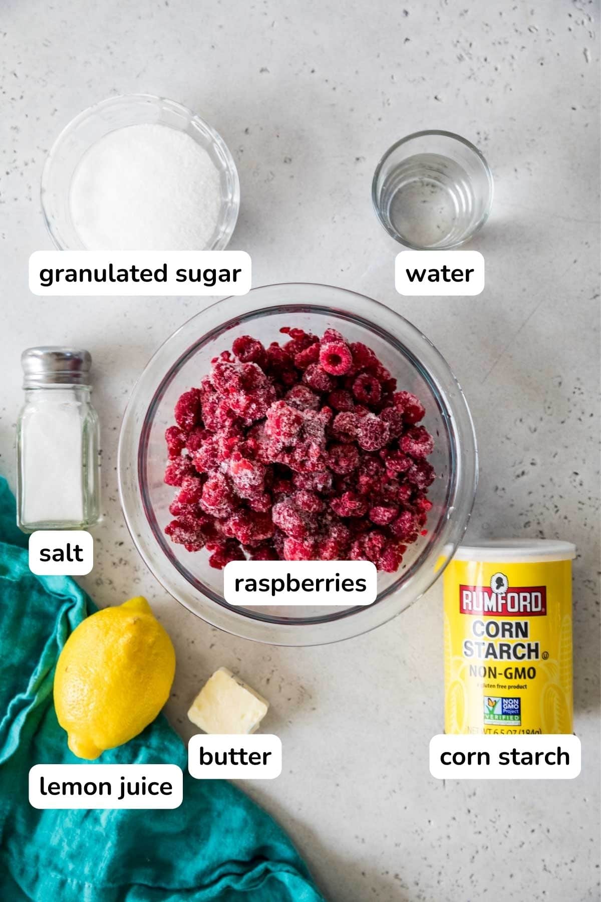 Overhead view of ingredients including sugar, raspberries, lemon, and more.