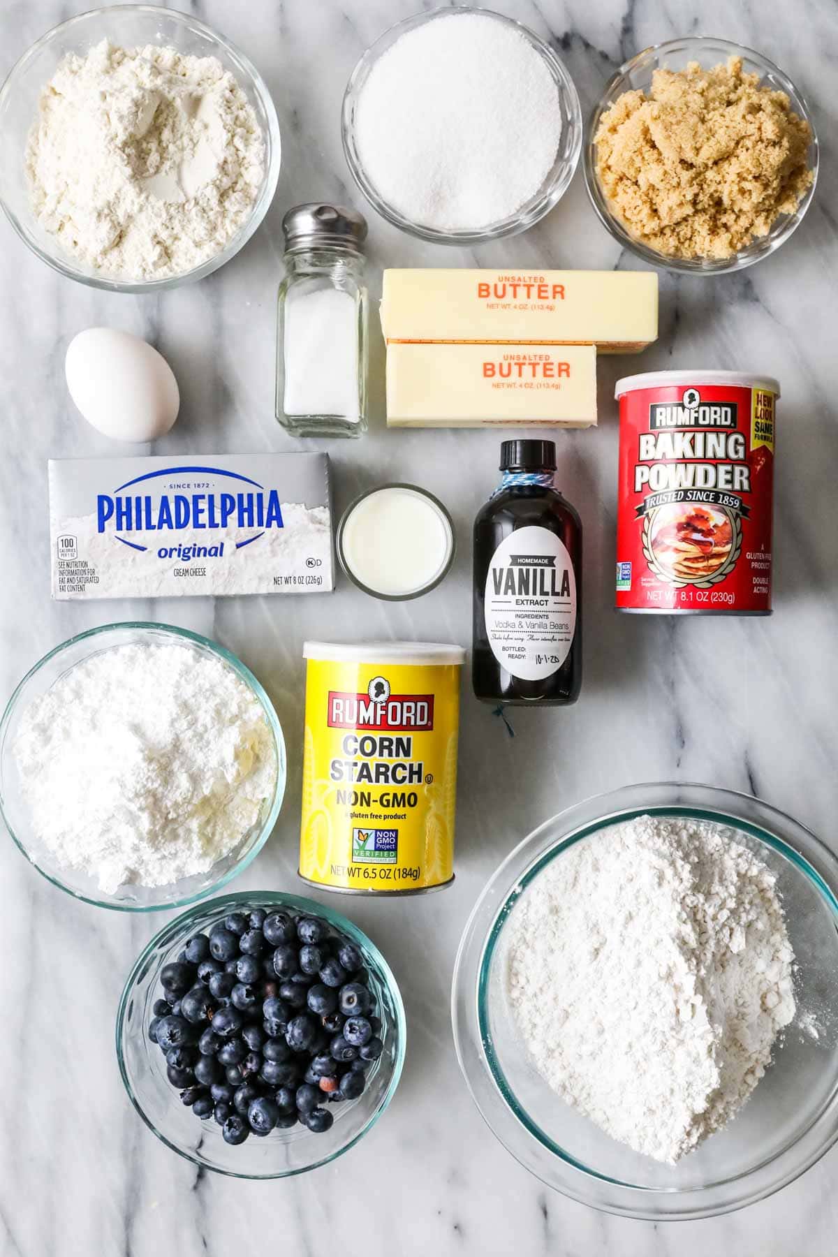 Overhead view of ingredients including flour, sugar, cream cheese, and blueberries.