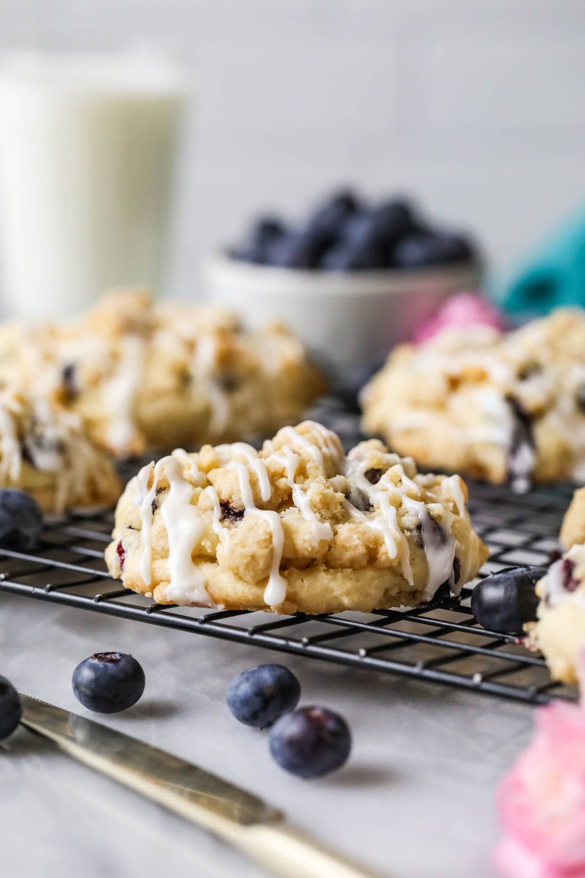 Cookies made with blueberries, streusel, and a drizzle of glaze on a cooling rack.