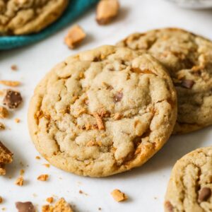 Two butterfinger cookies surrounded by crushed up butterfinger pieces.