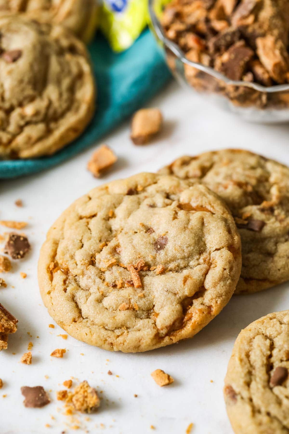 Two butterfinger cookies surrounded by crushed up butterfinger pieces.