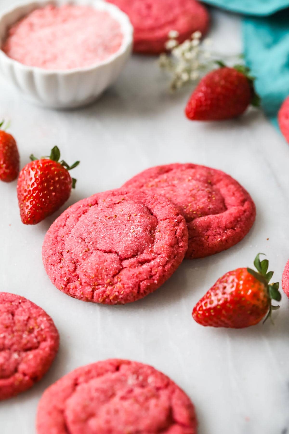 Round pink cookies made with freeze dried strawberries on a white countertop.
